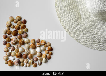 Summer decoration made from full heart seashells and summer straw hat on the white background. Stock Photo