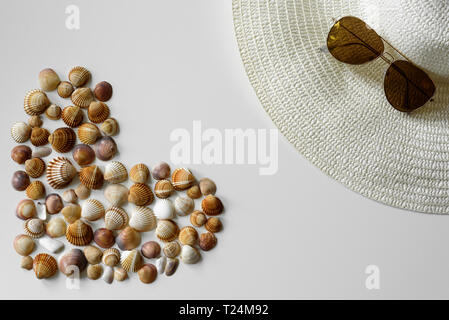 Full heart created from seashells and summer fashion set-up made from aviator sunglasses and sun straw hat. Stock Photo