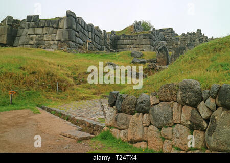 Stone paved way to the Sun Gate (INTIPUNKU written on the signpost) of Sacsayhuaman Incas citadel on the hilltop of Cusco, Peru Stock Photo