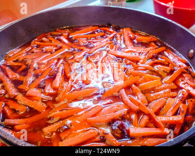Preparation of Uzbek pilaf - roasting meat and carrots in oil, zirvak, close-up Stock Photo