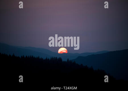 The Sun setting behind hills, Scotland, UK Stock Photo