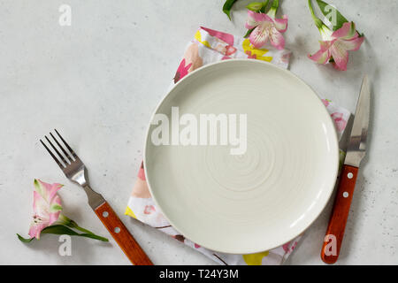 Spring or Mother's Day table setting. Plate, cutlery and napkin on white stone table. Top view flat lay background with copy space. Stock Photo