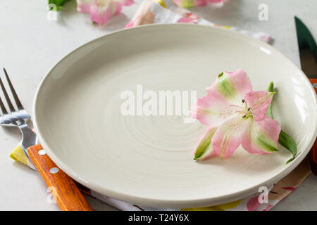 Spring or Mother's Day table setting. Plate, cutlery and napkin on white stone table. Copy space. Stock Photo