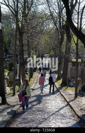 Tourists walking among Graves along an alley at pere lachaise cemetery, Paris, France Stock Photo