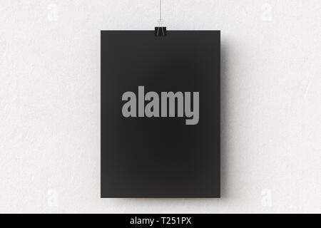 Blank black paper poster hanging on binder clip on white wall background Stock Photo