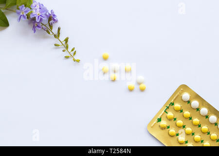 birth control pills of woman not want to have baby with purple flowers arrangement flat lay style on background white Stock Photo