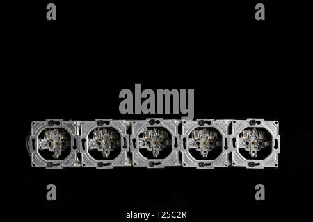 Five outlets in line, disassembled and mounted in black glass wall. Stock Photo