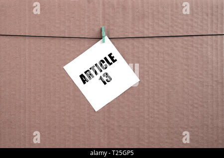 Article 13 inscription on white card on rope on a brown cardboard background. European copyright directive including article 13 is approved by europea Stock Photo