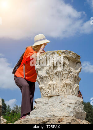 Tunisia, Tunis. September 17, 2016. Slim Caucasian woman tourist looks into the distance leaning on the capital of ancient column Stock Photo