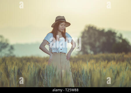 Beautiful asian woman having fun at barley field in summer at sunset time Stock Photo