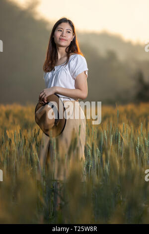 Beautiful asian woman having fun at barley field in summer at sunset time Stock Photo