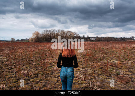 The girl is back in a black sweater. under the overcast sky. Dried up lake Stock Photo