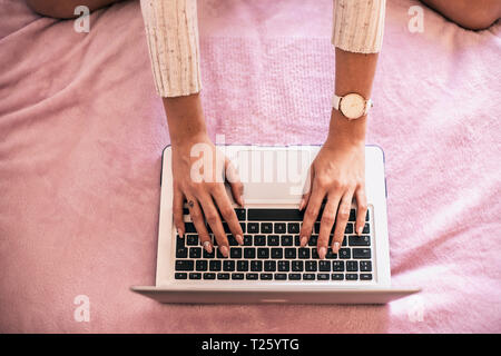 Woman's hand using laptop on bed, top view Stock Photo
