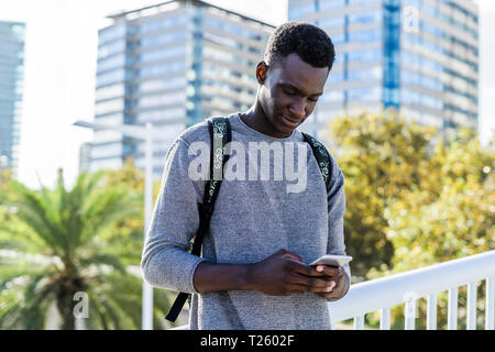 Young man standing on a bridge, using smartphone Stock Photo