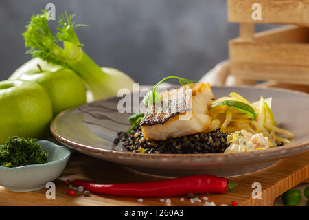 Hake marinated in lemon oil with black lentils with chili and celery, crayfish sauce Stock Photo