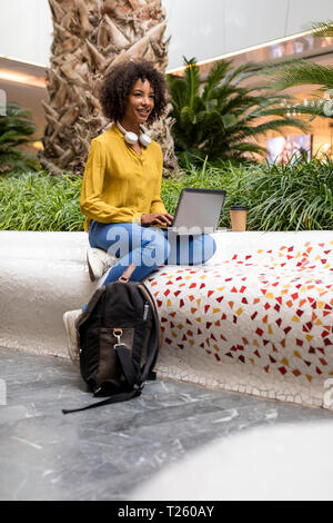 Portrait of smiling woman sitting on bench using laptop Stock Photo