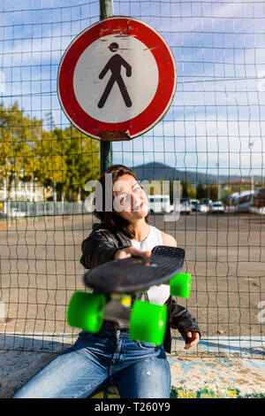 Portrait of smiling young woman holding skateboard Stock Photo