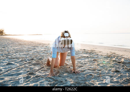 Thailand, woman using virtual reality glasses on the beach in the morning light Stock Photo