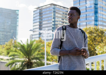Young man standing on a bridge, using smartphone Stock Photo