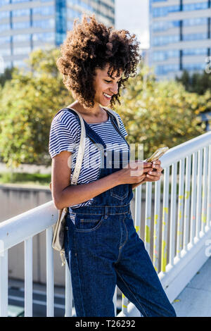 Young woman standing on a bridge, using smartphone Stock Photo