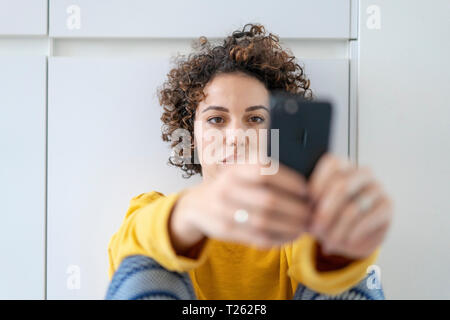 Woman using cell phone at home Stock Photo