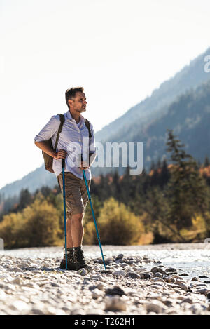 Austria, Alps, man on a hiking trip standing on pebbles at a brook Stock Photo