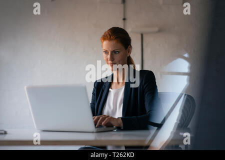 Businesswoman using laptop at desk in office Stock Photo