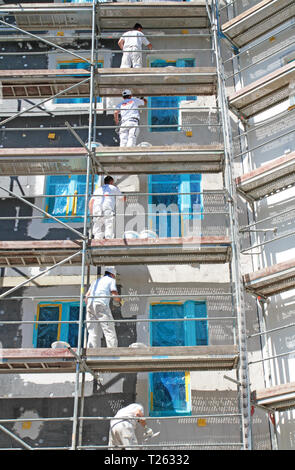 painter on scaffolding doing work on insulation Stock Photo