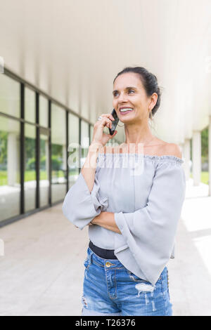 Portrait of smiling mature woman on the phone outdoors Stock Photo