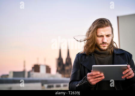 Germany, Cologne, portrait of bearded young man using digital tablet Stock Photo