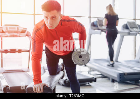 A man dumps triceps on the background of treadmills at the gym Stock Photo