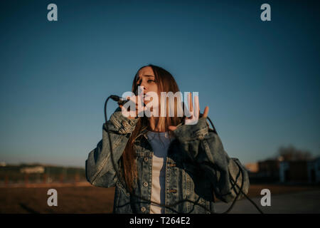 Young woman singing with a microphone outdoors Stock Photo