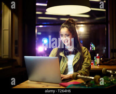 Smiling young woman using laptop on table Stock Photo