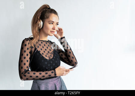 Young, elegant woman, wearing headphones, using smartphone Stock Photo