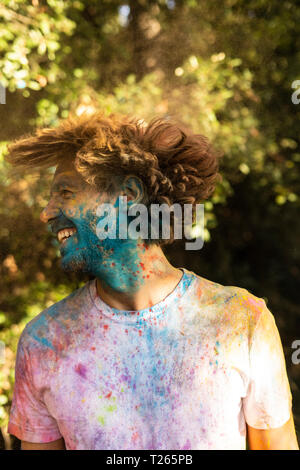 Man shaking his head, full of colorful powder paint, celebrating Holi, Festival of Colors Stock Photo