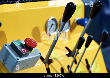 Close-up of a yellow control panel and security red stop button in the industrial machine . Stock Photo