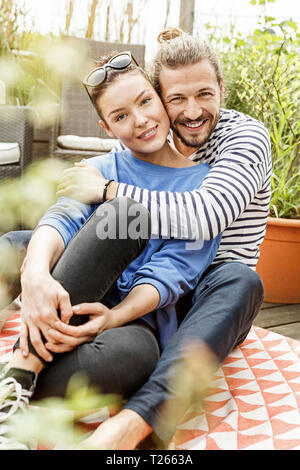 Young couple relaxing on their balcony,  embracing Stock Photo