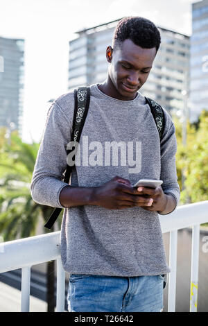 Young man standing on a bridge, using smartphone Stock Photo