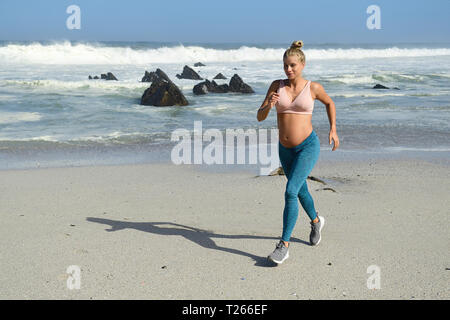 Pregnant woman jogging on the beach Stock Photo