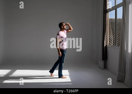 Man standing in a loft looking out of window Stock Photo