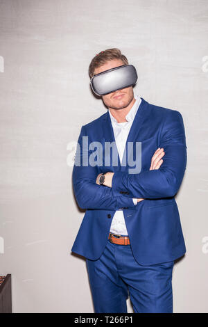 Young man wearing blue suit using Virtual Reality Glasses Stock Photo