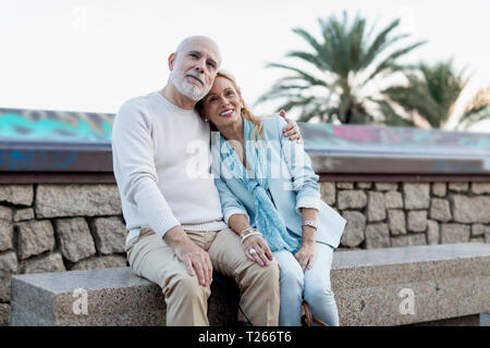 Spain, Barcelona, happy senior couple embracing on a bench Stock Photo