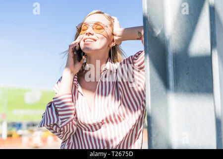 Portrait of smiling young woman on the phone enjoying sunlight Stock Photo
