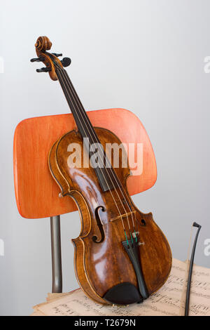 Violin, bow and sheet music on wooden chair, close-up Stock Photo