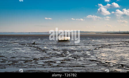 A boat in the Oare Marshes with the North Sea coast of Kent in the background, near Faversham, Kent, England, UK Stock Photo