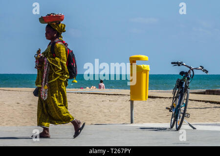 African woman in traditional clothes selling small jewelry on the beach, Valencia Malvarrosa Spain Stock Photo