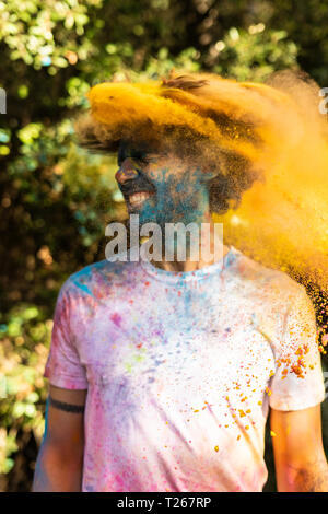 Man shaking his head, full of colorful powder paint, celebrating Holi, Festival of Colors Stock Photo