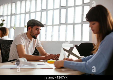 Colleagues using laptops at desk in office Stock Photo
