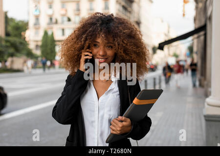 Young woman using smartphone, laptop bag Stock Photo