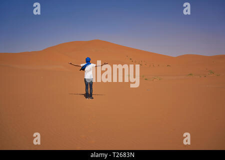 Morocco, back view of man standing on desert dune Stock Photo